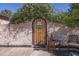 Charming wooden garden door set into a brick wall, framed by white flowers and surrounded by comfortable seating at 16322 E Fairview St, Gilbert, AZ 85295