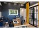 Elegant home office with navy blue walls, striking artwork, and a rustic desk, creating an inspiring workspace at 16322 E Fairview St, Gilbert, AZ 85295