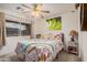 Bright bedroom featuring a ceiling fan, floral bedding, and a large window providing natural light at 16424 W Cottonwood St, Surprise, AZ 85388