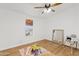 Bright bedroom featuring wood-look floors, ceiling fan, a window, and room for a play area at 16643 W Quail Run Rd, Surprise, AZ 85378