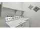 Functional laundry room featuring a washer and dryer set, and convenient overhead storage shelves at 16729 N 157Th Ave, Surprise, AZ 85374