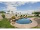 Beautiful backyard pool with decorative rock waterfall, lush landscaping, and mature palm trees beyond block wall at 17790 N 66Th Ln, Glendale, AZ 85308