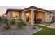 Charming back exterior featuring covered patio, a dining area, landscaping, and a gravel bed with lush plants at 19022 W Rose Ln, Waddell, AZ 85355
