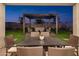Stunning back patio area with a pergola, dining table, seating area, artificial turf, and hardscape design elements at 19022 W Rose Ln, Waddell, AZ 85355
