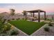 Beautiful backyard featuring a covered patio with seating and an artificial grass lawn at 19022 W Rose Ln, Waddell, AZ 85355