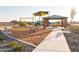 Sidewalk view of neighborhood park featuring a swing set, playground slide, picnic shelter and a community bench at 19022 W Rose Ln, Waddell, AZ 85355