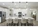 Bright kitchen with white cabinets, stainless appliances, large island with seating, and modern pendant lighting at 19022 W Rose Ln, Waddell, AZ 85355