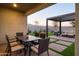 Outdoor patio area featuring a dining set, pergola with comfortable seating, and manicured artificial turf at 19022 W Rose Ln, Waddell, AZ 85355