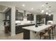 A stylish kitchen featuring dark cabinets, a white backsplash, and a spacious island with counter seating at 19045 W Rose Ln, Waddell, AZ 85355
