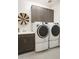 Modern laundry room with sleek washer and dryer set, decorative storage cabinets, and utility sink with modern fixtures at 19045 W Rose Ln, Waddell, AZ 85355
