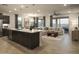 Open-concept living space with a large island, dining area, and comfortable sectional sofa at 19045 W Rose Ln, Waddell, AZ 85355