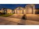 Exterior shot of a well-lit home showcasing its manicured lawn and inviting facade at twilight at 21617 S 229Th Way, Queen Creek, AZ 85142