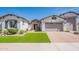 Charming single-story home boasts a well-manicured lawn and a neutral-toned exterior with a brick driveway at 21617 S 229Th Way, Queen Creek, AZ 85142