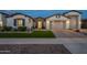 Well-lit home with a three-car garage, artificial lawn, and professional landscaping at 21617 S 229Th Way, Queen Creek, AZ 85142