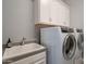 The laundry room offers white cabinets, modern machines, a sink with counter space, and neutral tones at 21617 S 229Th Way, Queen Creek, AZ 85142