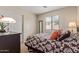 Comfortable bedroom with a patterned bedspread, soft lighting, and sliding closet doors at 22300 N Kingston Dr, Maricopa, AZ 85138