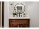 Updated half bathroom with wood vanity, quartz countertop, round mirror, and stylish fixtures at 23405 N 84Th St, Scottsdale, AZ 85255