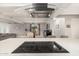 Modern kitchen with black cooktop island, open to living and dining areas with neutral gray walls and white trim at 23405 N 84Th St, Scottsdale, AZ 85255