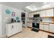 Kitchen view with laundry room, white cabinets, tile flooring, and a kitchen cart at 2434 W Eugie Ave, Phoenix, AZ 85029