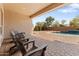 Inviting covered patio with brick pavers, outdoor chairs, and views of a refreshing pool and lush landscaping at 3557 S Halsted Ct, Chandler, AZ 85286
