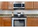 Well-equipped kitchen featuring stainless appliances, granite countertops, and wood cabinetry, offering a modern cooking space at 3557 S Halsted Ct, Chandler, AZ 85286