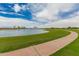 Scenic community pond with a walking path, lush green grass, and mature palm trees at 3749 E Sagebrush St, Gilbert, AZ 85296