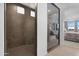 Modern bathroom showcases a sleek glass shower, tile walls, and access to the main bedroom at 40610 W Desert Fairways Dr, Maricopa, AZ 85138