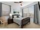 Bright bedroom features a wood bed frame, ceiling fan, and windows offering natural light, creating a serene atmosphere at 40610 W Desert Fairways Dr, Maricopa, AZ 85138