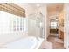 Primary bathroom showcasing a soaking tub, glass enclosed shower, and a view into the primary suite at 4313 N 161St Ave, Goodyear, AZ 85395