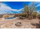 Expansive backyard with a sparkling blue pool, stone fire pit, lush landscaping, and a charming patio area at 4445 E Coconino St, Phoenix, AZ 85044