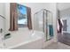 Bright bathroom with a soaking tub, glass-enclosed shower, and large window offering natural light at 5153 W Topeka Dr, Glendale, AZ 85308