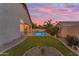 A spacious backyard with a pool, lush grass, and ambient lighting, perfect for relaxation and entertaining at 735 W Ivanhoe St, Gilbert, AZ 85233