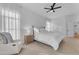 Light-filled main bedroom featuring a plush armchair, neutral walls, soft carpet, and a ceiling fan at 735 W Ivanhoe St, Gilbert, AZ 85233