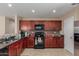 Well-lit kitchen with dark wood cabinets, black appliances, granite countertops, and durable tile flooring at 749 E Desert Moon Trl, San Tan Valley, AZ 85143