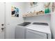 Well-lit laundry room featuring a modern washer and dryer with storage shelves for an organized space at 8341 W Palo Verde Ave, Peoria, AZ 85345