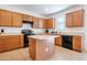 Kitchen with wood cabinets, island, and black appliances including oven and dishwasher at 10221 W Puget Ave, Peoria, AZ 85345