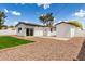 A backyard with grass, gravel landscaping, and a patio area with a sliding glass door at 1038 N 78Th Pl, Scottsdale, AZ 85257