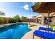 Backyard view of a sparkling blue swimming pool surrounded by lounge chairs and a covered patio at 12526 S 176Th Ave, Goodyear, AZ 85338