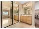 Bright bathroom with double sinks, light wood cabinetry, large mirror, and a glimpse of a soaking tub at 13336 W Via Caballo Blanco --, Peoria, AZ 85383