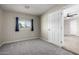 Bedroom showcasing neutral walls, gray carpet, a window with blue curtains, and a glimpse into another room at 14842 N 36Th St, Phoenix, AZ 85032