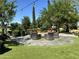Outdoor fire pit area with comfortable seating, surrounded by lush landscaping and mature trees at 156 E Leverenz Ave, Queen Creek, AZ 85140