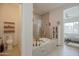 Bright bathroom featuring a large soaking tub with a decorative tile surround and a connected powder room for added convenience at 17985 W Jojoba Rd, Goodyear, AZ 85338