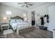 Bright bedroom featuring a ceiling fan, wood floors, and a cozy woven storage bench at the foot of the bed at 17985 W Jojoba Rd, Goodyear, AZ 85338