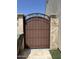 Elegant brown metal gate set within stone pillars, adding a touch of charm and security to the property at 17985 W Jojoba Rd, Goodyear, AZ 85338