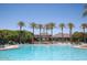 Community pool with chairs, umbrellas, palm trees and a building in the background at 17985 W Jojoba Rd, Goodyear, AZ 85338