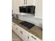 Modern kitchen features granite countertops, sleek white cabinets, and a stylish stainless steel gas cooktop at 17985 W Jojoba Rd, Goodyear, AZ 85338