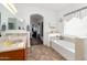 Bright bathroom features double sinks, tile flooring, soaking tub, and arched doorway to adjoining room at 18325 W Port Au Prince Ln, Surprise, AZ 85388