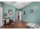 Bedroom features wood-look floors, pale green walls, a desk, and a cozy bed at 18325 W Port Au Prince Ln, Surprise, AZ 85388