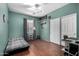 Bedroom with wood-look floors, pale green walls, and a ceiling fan for added comfort at 18325 W Port Au Prince Ln, Surprise, AZ 85388