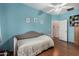 Bright blue bedroom featuring laminate floors, a ceiling fan, and a neutral sofa at 18325 W Port Au Prince Ln, Surprise, AZ 85388